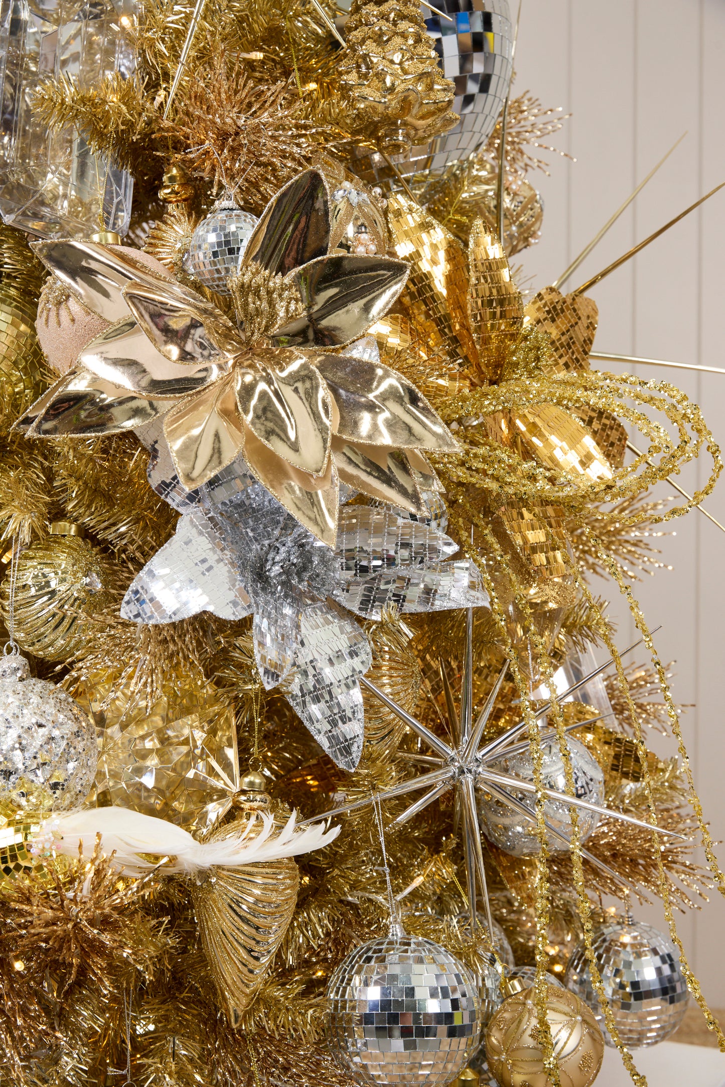 Close-up of Holly & Ivy Stardust Christmas tree décor with gold florals, disco baubles and shimmering picks.